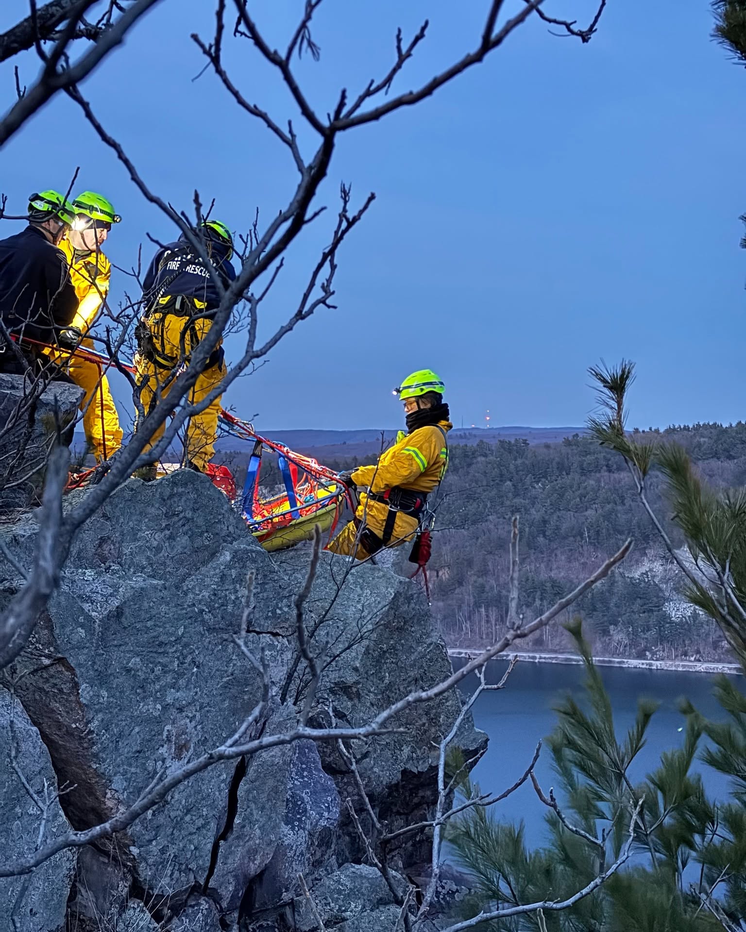 Rescue personnel operating with a litter and rope system above Devil’s Lake.