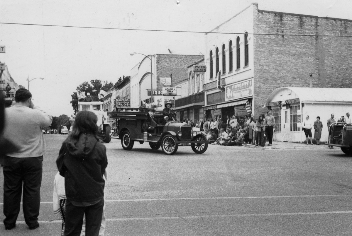 Historic fire apparatus traveling through a downtown parade in 1970.